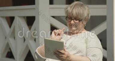 阳光明媚的一天，在<strong>养老院</strong>拍摄的带有眼镜的平板电脑拍摄的老年妇女肖像